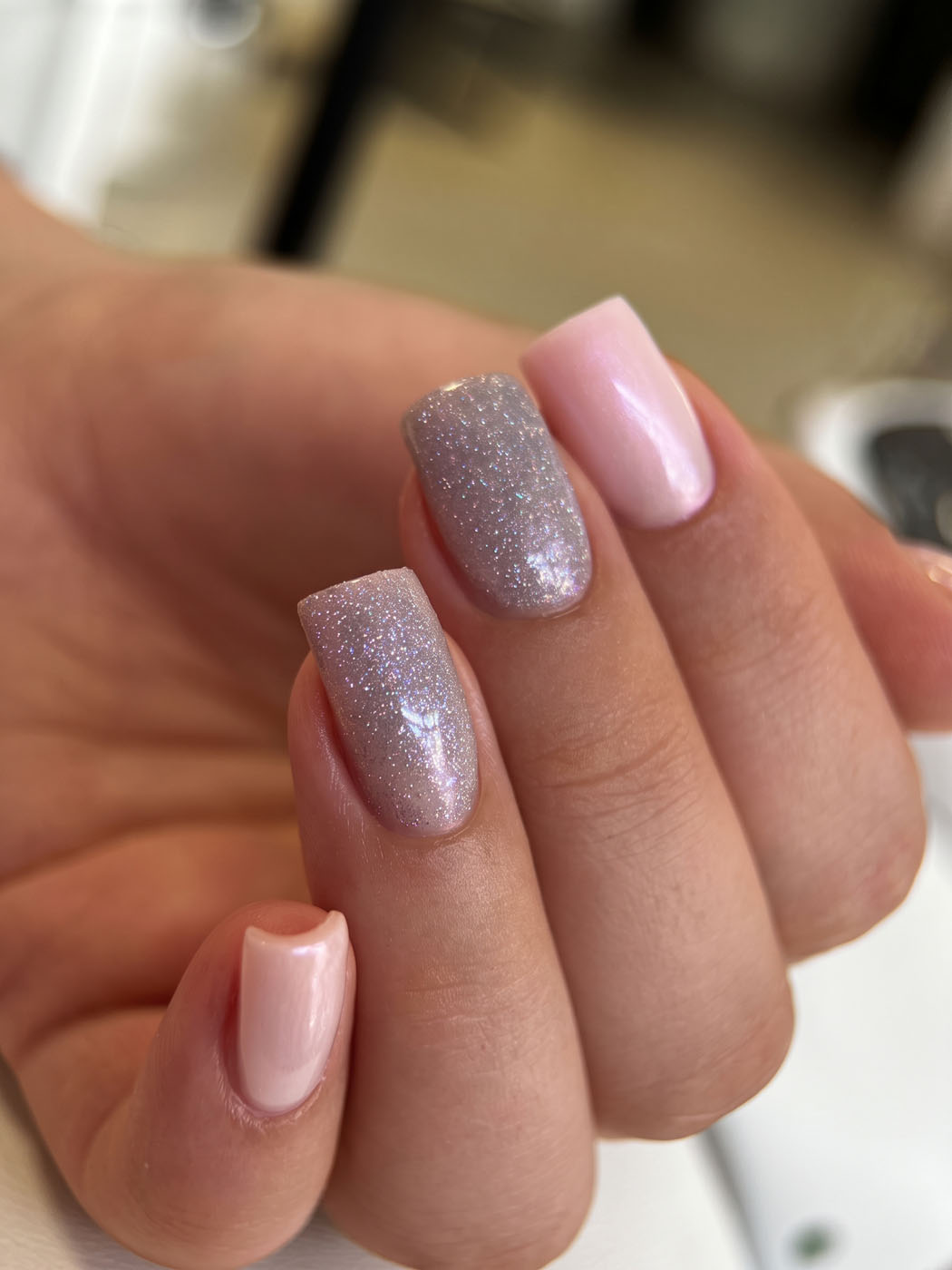 Zartrosa Shellac mit silbernem Glitzer auf zwei Nägeln